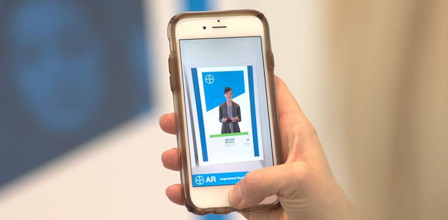 Bayer Compliance AR, using the app on a smartphone, pointed at a banner